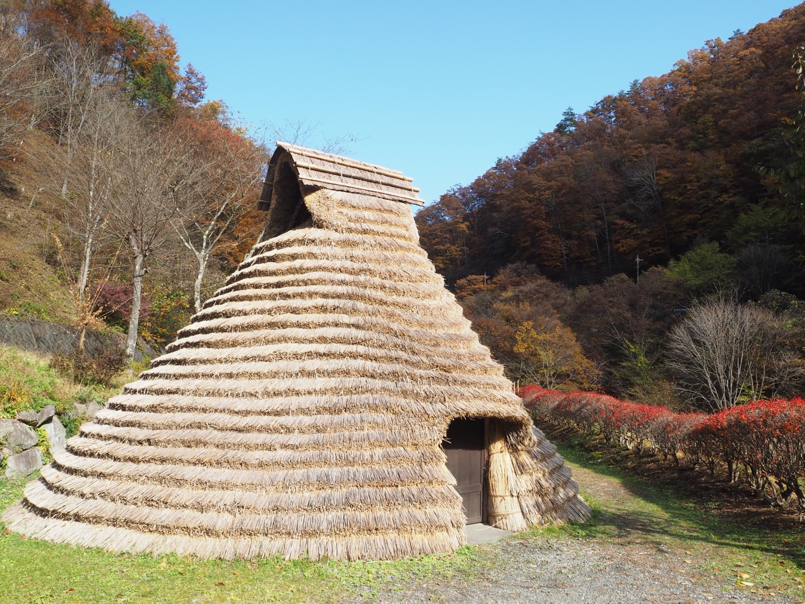 紅葉の山を背にした原始村の竪穴住居